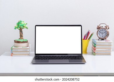 Open laptop mock-up at the child's workplace with books and colored pencils. Back to school online learning concept - Powered by Shutterstock