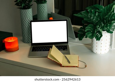Open laptop with white screen.
Empty open notebook.
Work in the evening.