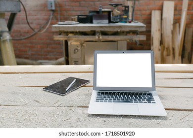 Open Laptop In A Woodshop With Isolated Screen On A Wooden Table