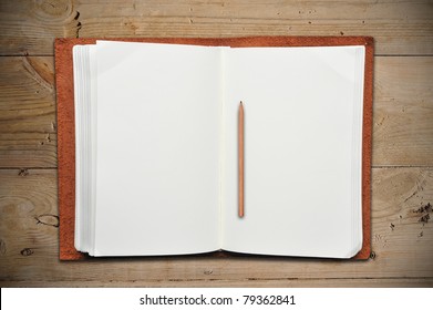 Open Leather Book With Vintage Pencil On Old Wooden Table