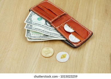 Open leather wallet with banknotes and crypto-coins on wooden desk.