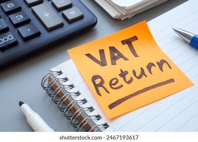Open ledger and sticky note with words VAT return.