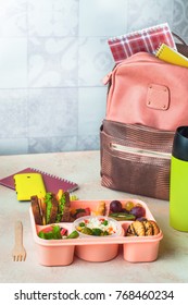 Open Lunch Box With Healthy Lunch With Sandwiches, Vegetable Salad, Fresh Grape And Kiwi, Rice With Grilled Brussels Sprouts And Nuts On The Table Near School Backpack; Selective Focus