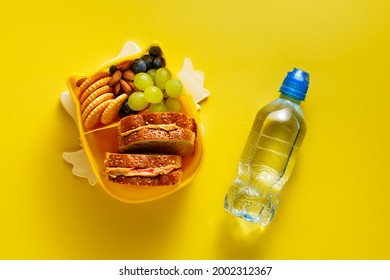 Open Lunch Box With Kid's Lunch With Peanut Butter Sandwiches, Cracker, Grapes, Almonds, Blueberries And Water Bottle. Top View, Flat Lay