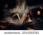 
Open magic book with flying autumn leaves and raven black feathers and glowing magical light. Halloween night season background poster. Witchcraft, spell, wizard and fantasy concept. 