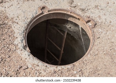 An Open Manhole On The Road. Dangerous Open Unsecured Hatch On The Road. Accident With Sewer Hatch In City. Concept Of Sewage, Repair Of Underground Communications