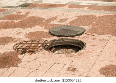 An Open Manhole On The Road. Dangerous Open Unsecured Hatch On The Road. Accident With Sewer Hatch In City. Concept Of Sewage, Repair Of Underground Communications