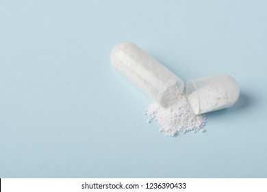 Open medical drug pill with white powder macro closeup on blue paper background