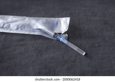 Open And Medical Syringe With Needle On Gray Denim Background