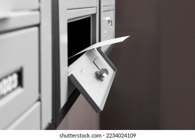 Open metal mailbox with envelope indoors, closeup view