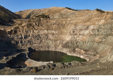 Open mining pit in mountain. Open-pit quarry, mine landscape, pond. Historical travel destination place Ak-Tyuz, Kyrgyzstan. Abandoned Kyrgyz mining and metallurgical plant. lead mining, deposit
