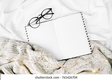 Open Mockup Planner And Glasses On Bed With Warm Plaid. Copy Space. Flat Lay, Top View