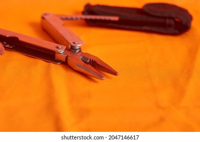 Open Multitool Pliers On Orange Background