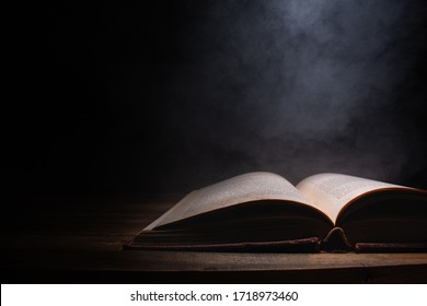 open a mysterious old book on wooden table, smoke float up from book