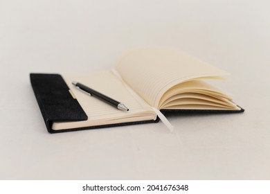 An open notebook with a ballpoint pen on a white background - Powered by Shutterstock