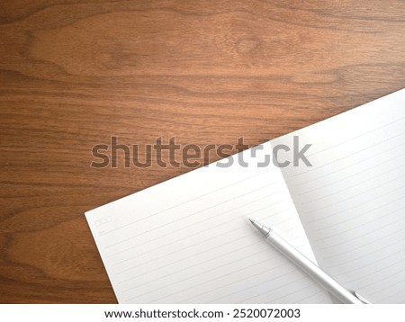 An open notebook and ballpoint pen on a desk