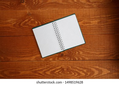 Open notebook with blank page on wooden floor in the background