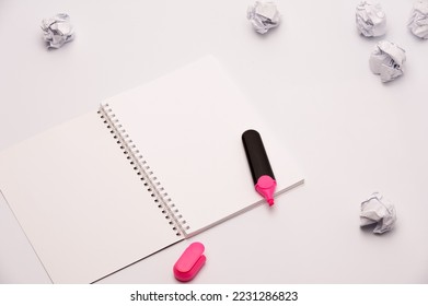 an open notebook and blank pages  pink marker   some crumpled pieces paper the white background