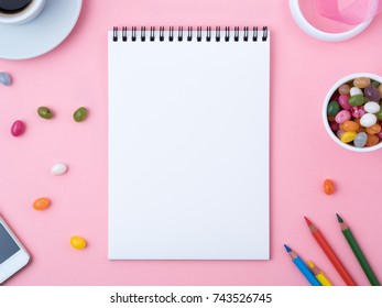 open notebook with a clean white sheet, caramel, lollipops,  mobile phone, crayon, cup of coffee, decorations on a pink bright table. Girl's workplace for creativity, plans and dreams. - Powered by Shutterstock