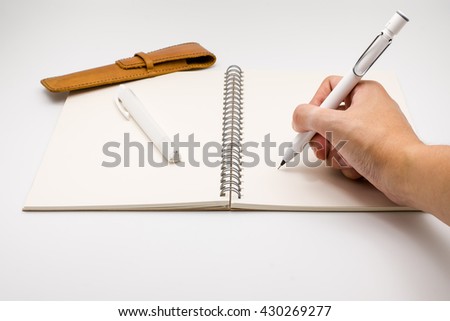 Open notebook with hand writing pencil rubber and pencilcase on white background