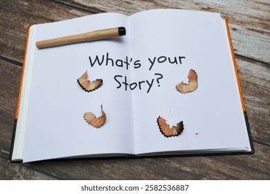 An open notebook invites creativity with a question and pencil alongside pencil shavings on a wooden table.