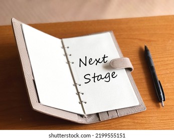 Open Notebook With Next Stage Letters And Ballpoint Pen