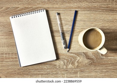 an open notebook for notes with a pencil and a cup of coffee on a wooden table with a copy space top view. High quality photo
