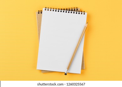 open notebook on corrugated yellow background with pencil top view, spiral notepad with blank sheet, flat lay. school concept, desktop of businessman.