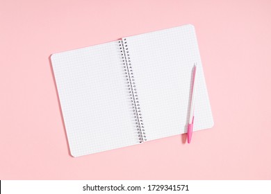 Open notebook on pink background. Spiral notepad and pen. Flat lay, top view, copy space