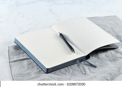 Open notebook on white marble background. Copy space.