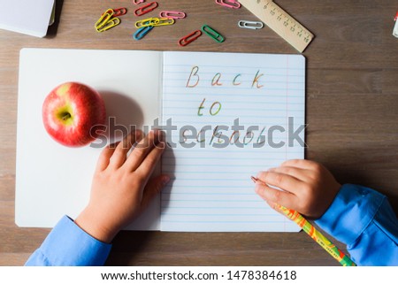 Open notebook, the page which is written Back to school, and the child hand with a colored pencil. Concept back to school.