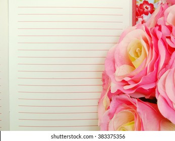 the open notebook paper with red lines and artificial roses flower