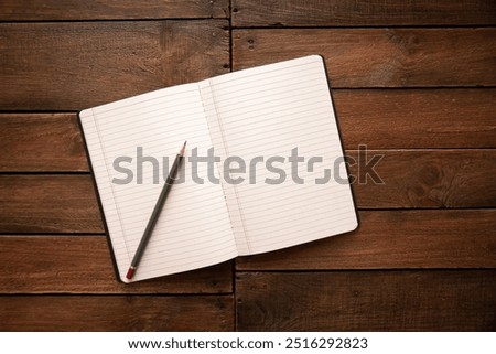 Open notebook and pencil on a rustic vintage wooden board