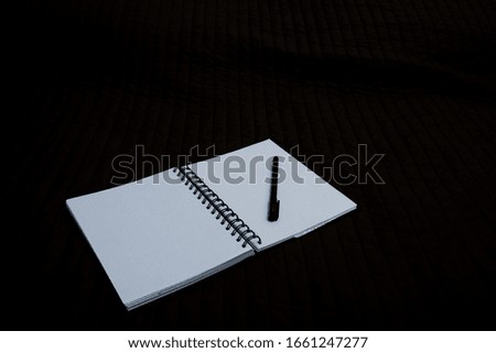 open notebook to point with a pen on a dark background