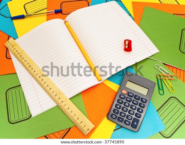 Open\
notebook sharpener ruler paper-clips calculator pencil and pen\
against the multicolored notebooks\
background