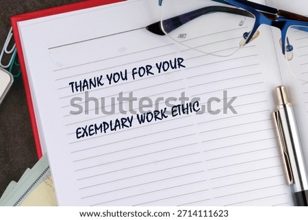 An open notebook showing a message that says Thank You For Your Exemplary Work Ethic. A pen and glasses sit on top of the notebook on a desk.