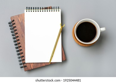 open notepad, cup of coffee, golden pen moose on gray background spiral notebook on table Business, planning, education, morning life working from home concept Top view Flat lay Mock up