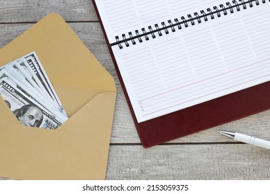 Open notepad of weekly envelope planner with money on a wooden table. Clipping path of meeting concept.space.