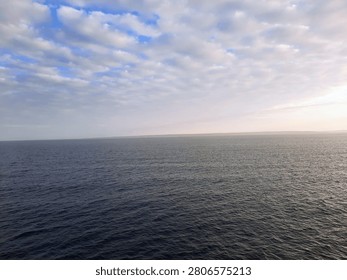 Open ocean under dramatic cloud formations during early morning, featuring a calm sea horizon and expansive seascape, water texture background