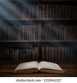 Open old book on a bookshelf background and the rays of light. Selective focus. Conceptual background on history, education, literature topics. - Shutterstock ID 1155961327