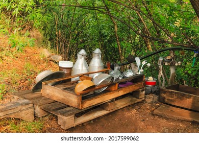 Open and old-style kitchen made of wood in the forest and fountain with water from the mountain. Wooden shelves and kitchen utensils.