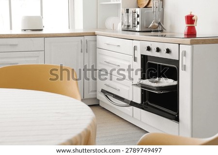 Open oven with baking dish in kitchen interior