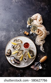 Open Oysters with spicy sauce and champagne on dark stone texture background copy space