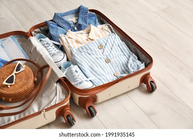 Open Packed Suitcase On Wooden Background