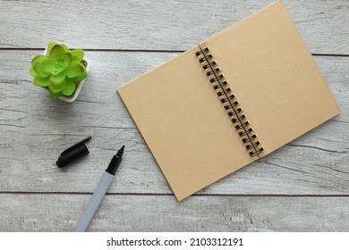 Open Pages Of Notepad With Black Marker Pen On Light Wooden Table With Potted Plant