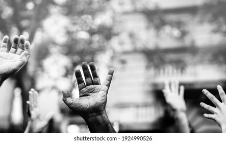 Open palm of a black hand and white hands raised in the air asking for freedom. Multicultural hands in a demonstration on street in black and white. Stop racism. Stop repression.