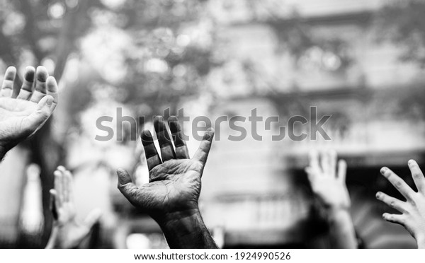 Open palm of a\
black hand and white hands raised in the air asking for freedom.\
Multicultural hands in a demonstration on street in black and\
white. Stop racism. Stop\
repression.
