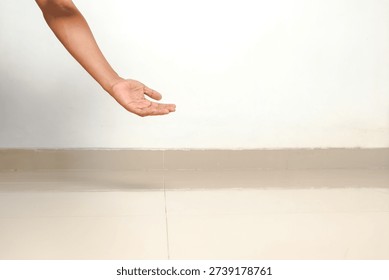 An open palm hand extends from the side, reaching forward against a simple white wall.