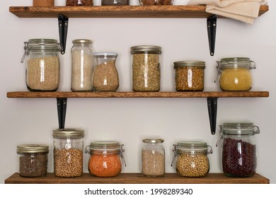 Open Pantry Wooden Shelves With Glass Storage Containers Filled With Grains And Legumes . Home Concept. Organic Food Concept. Ecology Concept.