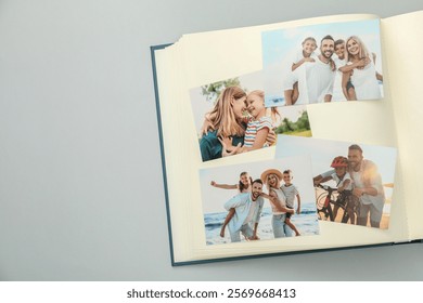 Open photo album with different photos on grey background, top view. Space for text